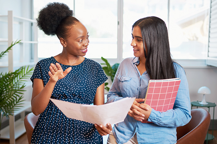 decorative image of two women talking in a work setting