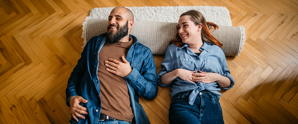 Couple laying on the floor with a rug under their heads